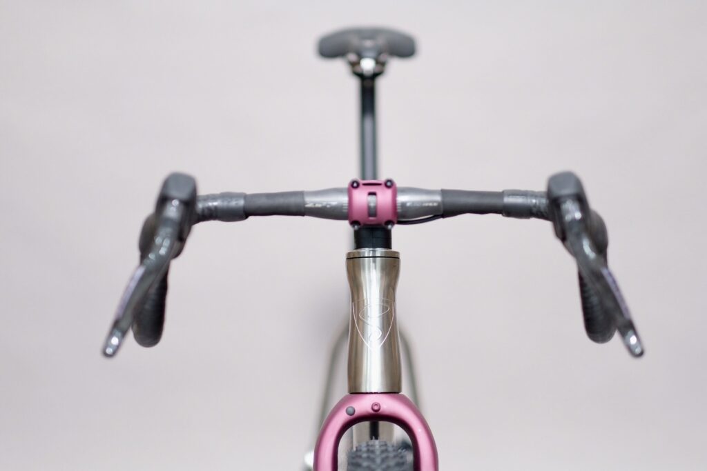 Close-up of an innovative bicycle handlebar with pink detail and practical grips for comfortable riding.