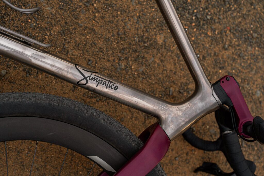 Close-up of the Simpatico logo on a raw brushed titanium Gamma Race frame
