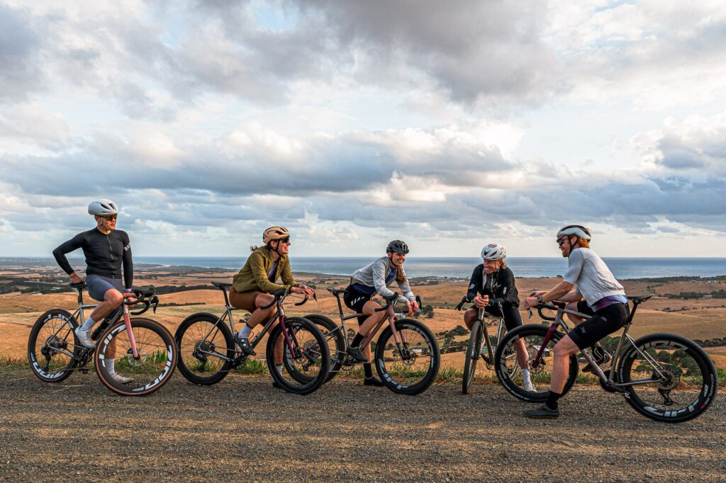 Riders with titanium gravel bikes stopped on a dry gravel road